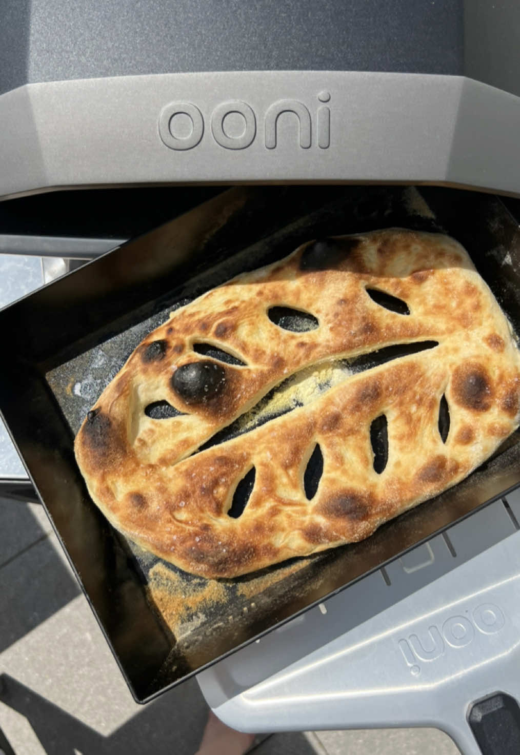 A post by @_lacebakes_ on TikTok caption: ad Have a spare pizza dough ball? Here are three ideas for how to bake it in the Koda 2 from @Ooni Pizza Ovens. What I love about the Ooni Koda 2: - Super easy to set up and heats up quickly - Temperature control for low, medium or high heats (ranging from 100C - 500C). - Designed to reduce hot and cold spots to ensure an even bake each time - The 14-inch stone is generously sized and the stone is extra thick which means it retains heat more efficiently. For all of the recipes, set pizza oven to medium low - stone temp 250-260C. Fougasse  1. Sprinkle some fine semolina on a 9x13 inch (23x33cm) metal baking tray. I’m using the medium Ooni Detroit-Style Pizza Pan.  2. Stretch pizza dough into an oval to nearly fill the tray and then using a pizza wheel, cut one long score down the middle. Then cut four diagonal scores on each side.  3. Use your fingers to open up the cuts you’ve just made, drizzle with extra virgin olive oil, sprinkle with sea salt and launch into the Koda 2.  4. After 3 minutes, turn the tray and bake until golden. Flip the bread and bake for another 2 minutes to ensure the bottom is toasted.  Garlic Butter Breadsticks  1. Stretch pizza dough into 8-inch square 2. Use pizza wheel to cut into 5 equal dough sticks and place into a 9x13 inch (23x33 cm) metal baking tray that has been scattered with semolina. 3. Bake for 2-3 minutes, rotate and bake for a further 2-3 minutes. Flip them over to brown bottom of breadsticks if needed. 4. Coat with a mixture of 1 Tbsp melted salted butter, 1/4 tsp garlic granules, 1/4 tsp dried parsley. Sprinkle over some freshly grated Parmesan. Pizza Dough Sandwich Roll 1. Stretch pizza dough into an oblong oval shape. Place onto semolina lined peel wand then launch into Koda 2.  2. Rotate after two minutes and continue rotating every two minutes until golden. Flip to crisp bottom for last two minutes. It should take about 12 minutes total.  Click the link in my bio to learn more about the Koda 2 and the full range from Ooni! #ooni #ooniambassador #koda2 