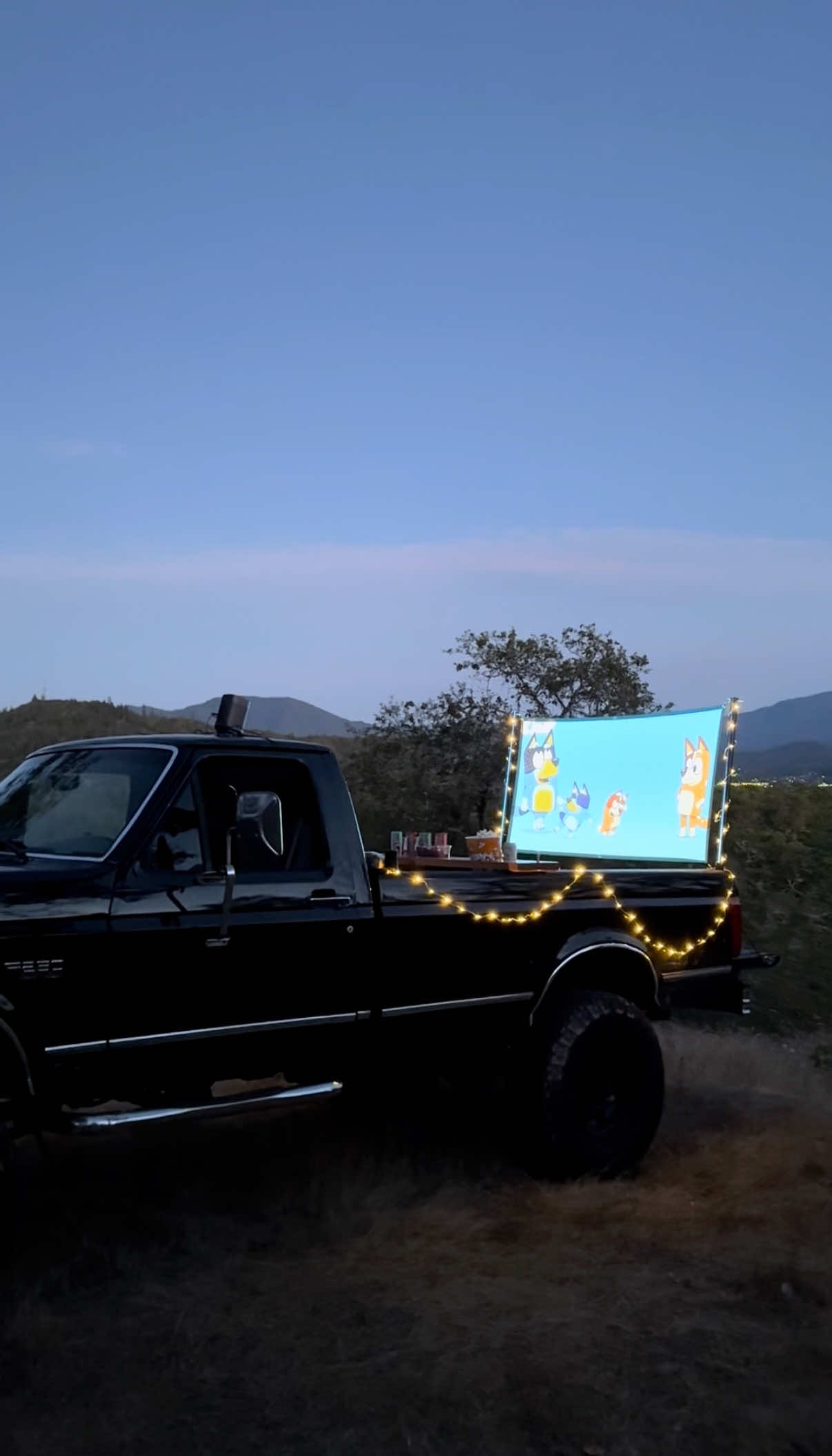 A post by @dadsocial on TikTok caption: We have done probably 20 of these back of truck movie nights over the past couple years and they are always such great memories. Do we watch the entire movie? Not usually. Do we spill a lot of popcorn? Always. Do we always want to do it again? Absolutely. Just going a little outside our normal family routine helps us create those core memories with our family. #truckmovie #movienight #movie 