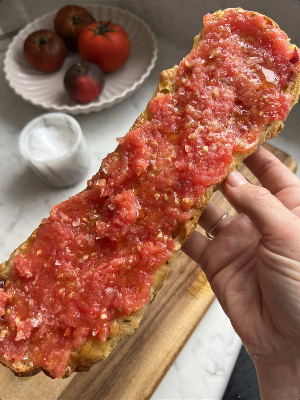 A post by @_lacebakes_ on TikTok caption: Pan con tomate…pa amb tomàquet…tomato bread 🍅 🍞  Whatever you want to call it, this is my favourite quick snack (or meal!) in the summertime. I don’t care if it’s breakfast, lunch, or dinner - I could eat this ALL. DAY. LONG. Simply toast a thick piece of bread or two halves of a crusty sandwich roll, rub the toasted bread with a garlic clove that’s been sliced in half, top with plenty of extra virgin olive oil, grated tomatoes (I drain off the excess liquid), a little more olive oil and flaky sea salt. You can rub the tomatoes directly onto the bread if they’re ripe enough and you prefer to do it that way 🍅 #asmr #asmrfood #asmrcooking #pancontomate #toast  #paambtomaquet  #spanishtapas #spanishfood #tomate #quickmeal #oliveoil #healthyrecipe #quickrecipe #healthy #vegan #yummy #foodporn #seasalt 