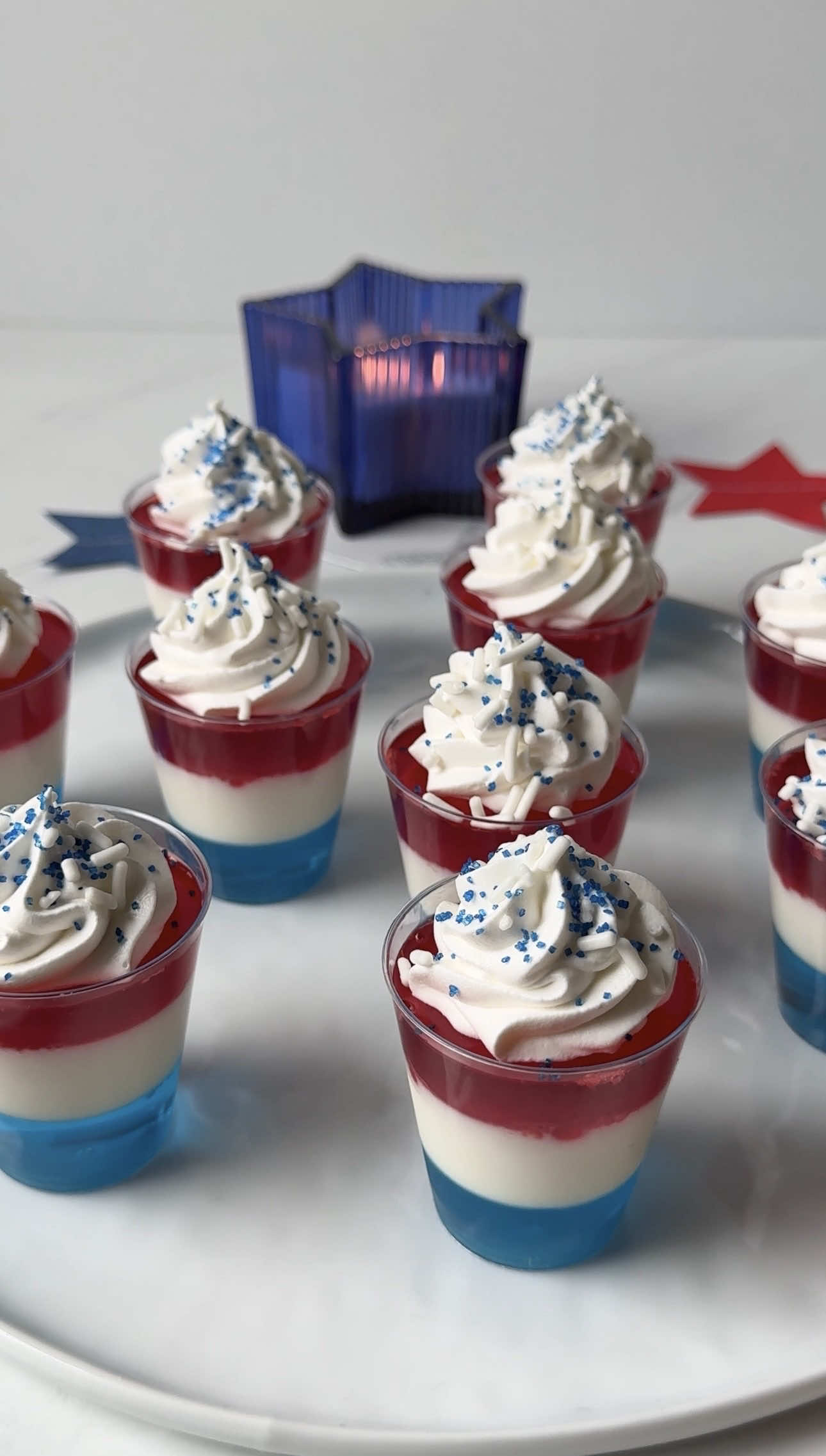 A post by @cocktails on TikTok caption: These red, white & blue Jell-O shots are the most festive way to celebrate the 4th. 🎆 Blue Layer: -3 oz. blue Jell-O mix -1 cup boiling water -1/2 cup cold water -1/2 cup vodka White Layer: -2 packets gelatin -1/2 cup cold water -1 cup boiling water -1/2 cup vodka -1 can sweetened condensed milk Red Layer: -3 oz. red Jell-O mix -1 cup boiling water -1/2 cup cold water -1/2 cup vodka Other: -whipped cream -sprinkles #redwhiteblue #jelloshots #jello #fourthofjuly #vodka