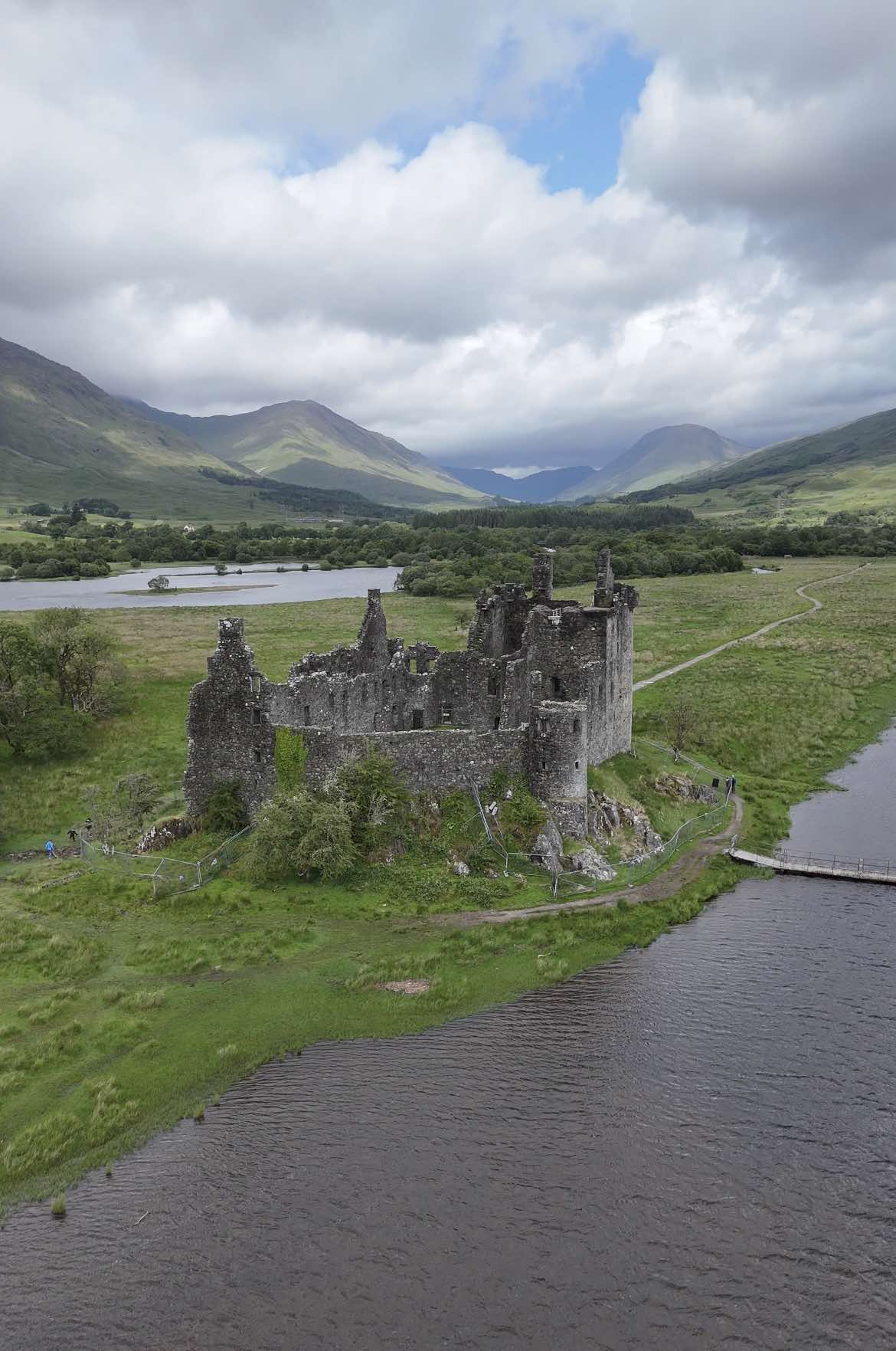 A post by @castlesofscotland on TikTok caption: Kilchurn Castle is located on Loch Awe and set against the backdrop of the mountains of Tyndrum. Kilchurn Castle was built around 1450 by Sir Colin Campbell, first Lord of Glenorchy. The land on which the castle stands had been granted to Colin in 1432 to ensure his loyalty following the sudden death of his elder brother, Gillespic. Colin’s descendants, the Campbells of Glenorchy (later earls of Breadalbane), were the most powerful of the numerous cadets of Clan Campbell. Indeed, there were times when this branch almost rivalled the clan chiefs, the earls of Argyll, for supremacy. Kilchurn Castle originally consisted of the courtyard and five-storey tower house, containing a hall, private chambers, a cellar and prison. Colin’s son Duncan, the 2nd Lord, added the laich hall in the courtyard before his death at the Battle of Flodden in 1513. Colin, the 6th Lord, added the four angle-turrets on the top of the tower house. Similar to many other castles, Kilchurn was subject to the changing political climate of early modern British politics. In 1689 Sir John Campbell of Glenorchy, 1st Earl of Breadalbane, retired to his ancestral seat and set about converting it into a garrison stronghold. The tower house was converted into accommodation for officers, while a barracks housing 200 men was built on the north side of the courtyard. The barracks block remains relatively complete, and is today the oldest surviving barracks on the British mainland During the Jacobite rebellions of 1715 and 1745 the castle acted as a government garrison. The Glenorchy-Campbell family continued to own the castle until around 1760. It was abandoned after being permanently damaged by a devastating lightning strike. It then remained largely undisturbed, as it fell apart due to decades of neglect. Today, Kilchurn is in the care of Historic Environment Scotland. Although it stands open to the elements, several wooden staircases and walkways built into its fabric allow visitors to climb the original five-story tower and other parapets. #scotland #castle #braveheart #gameofthrones #traveltiktok #history #bucketlist #landscape #outlander #visitscotland #scottishtiktok #beautifuldestinations #exploremore #adventure #fyp 
