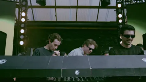 A post by @partyshirt on TikTok caption: One of our unreleased w/ our brother @Andre Zimmer 🤫 Our full set for Home Again Berlin is out now #djset #housemusic #techno #festival 