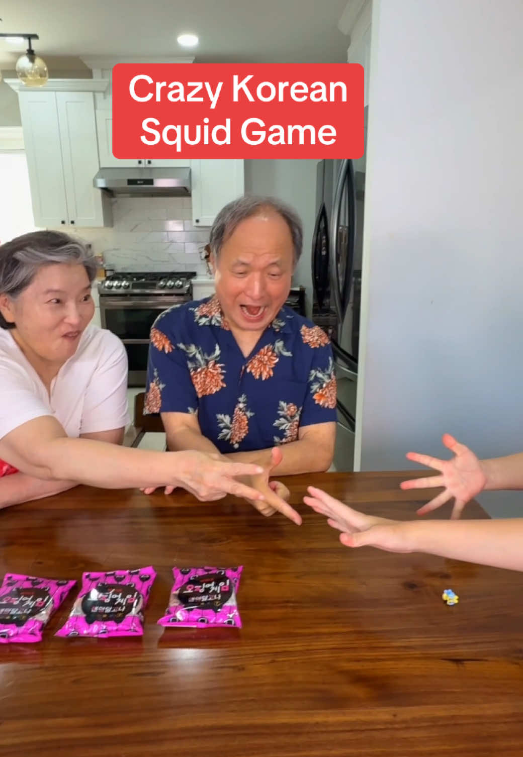 A post by @crazykoreancooking on TikTok caption: My little niece brought dalgona and wanted to compete with mom and dad just like in @Netflix Squid Game. Dalgona is actually a very nostalgic snack and game for us Koreans. 40 years ago in Korea I remember paying 100 WON to a street vendor and they would give you sugar in a metal ladle. You squat in front of a little fire and melt the sugar and add baking soda and mix like crazy. Then the vendor ajuhssi throws it on a board and flatten it and use a cookie cutter like metal to put a shape in it. If you cut the shape out with a needle without breaking it, you get a prize candy. Oh how I miss those days! #dalgona #SquidGame #squidgamenetflix #koreanfood #kdrama 