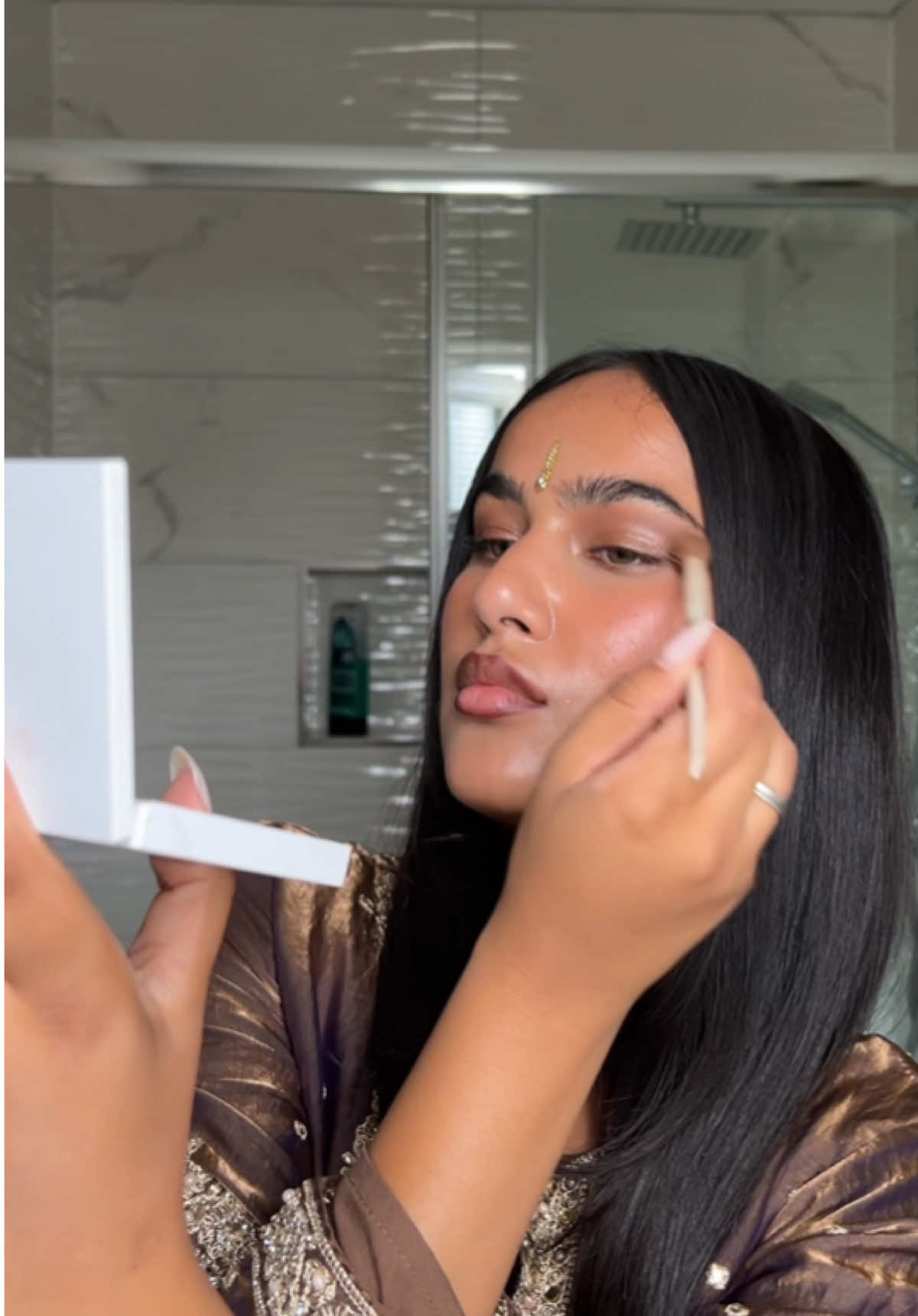 A post by @davinakareer on TikTok caption: touch ups 🤎 punjabi edition  @Kylie Cosmetics eyeshadow  @NARS Cosmetics eyeshadow  @rhode skin pocket blush sleepy girl  @maccosmetics lip glaze in root for me  @makeupbymario lip gloss  #grwm #makeup #punjabi #sharara #bindi #india #browngirlmakeup #maccosmetics #maclipliner #nars #kyliecosmetics #rhode #rhodeskin #pocketblush 