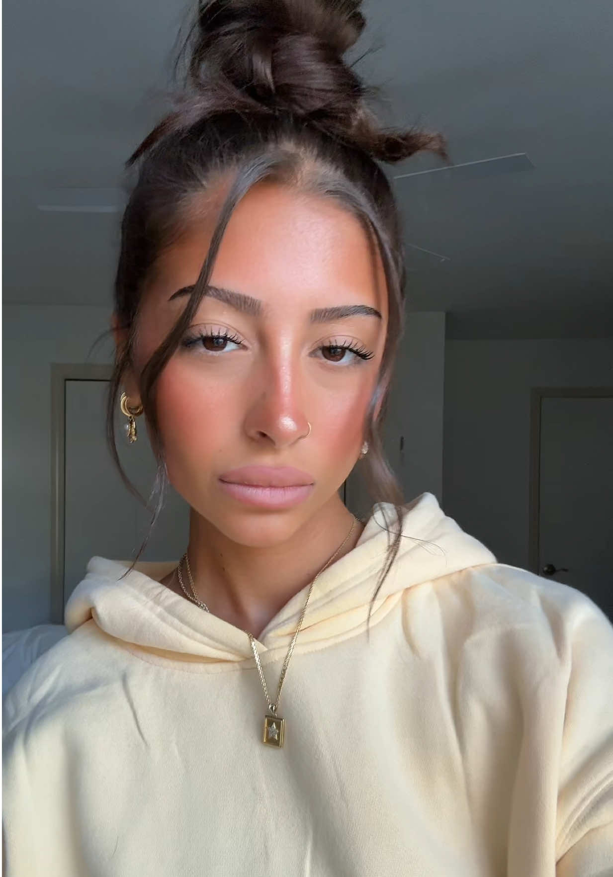 A post by @annaappetizer on TikTok caption: i usually hate front pieces hanging out of my hair buns but i actually like this one #butteryellow #messybun #outfitinspo 